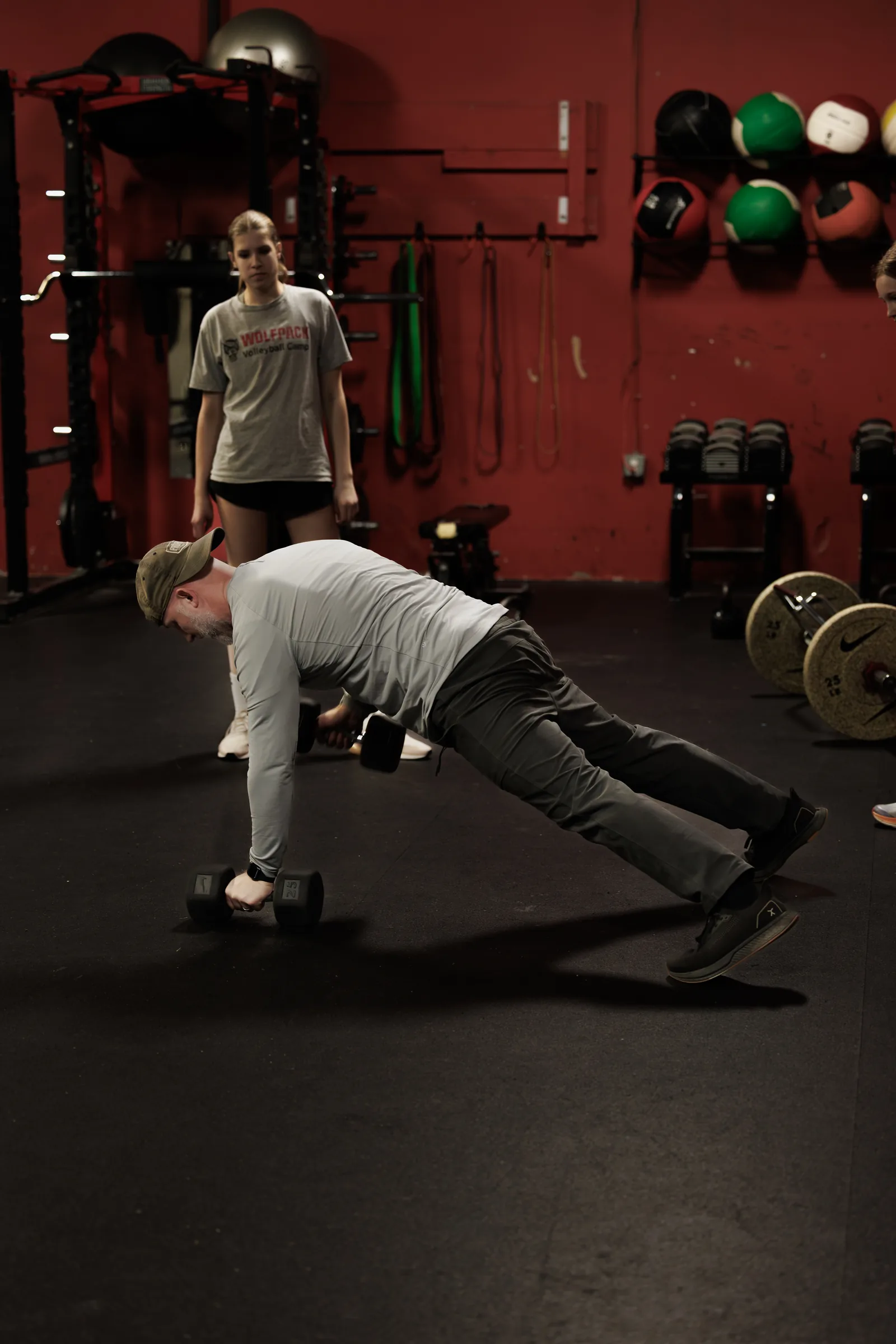 Coach Aaron Larmore demonstrating a plank row on the gym floor while an athlete watches