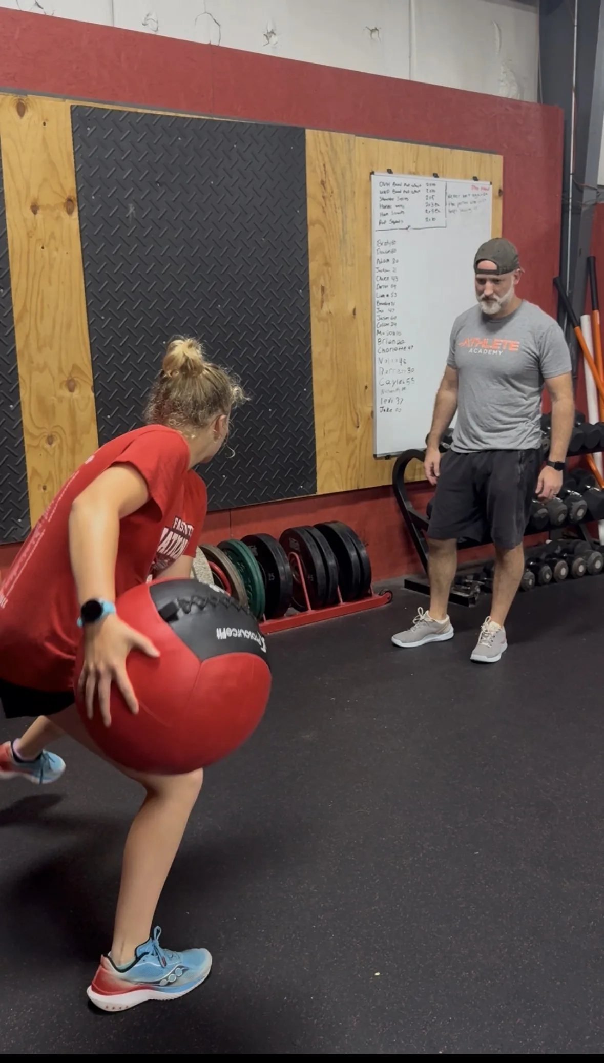 An athlete loading into a rotational medicine ball throw with a coach watching from the side
