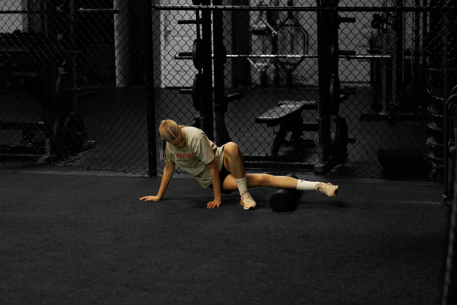 An athlete rolling out her thigh on the gym floor after a session