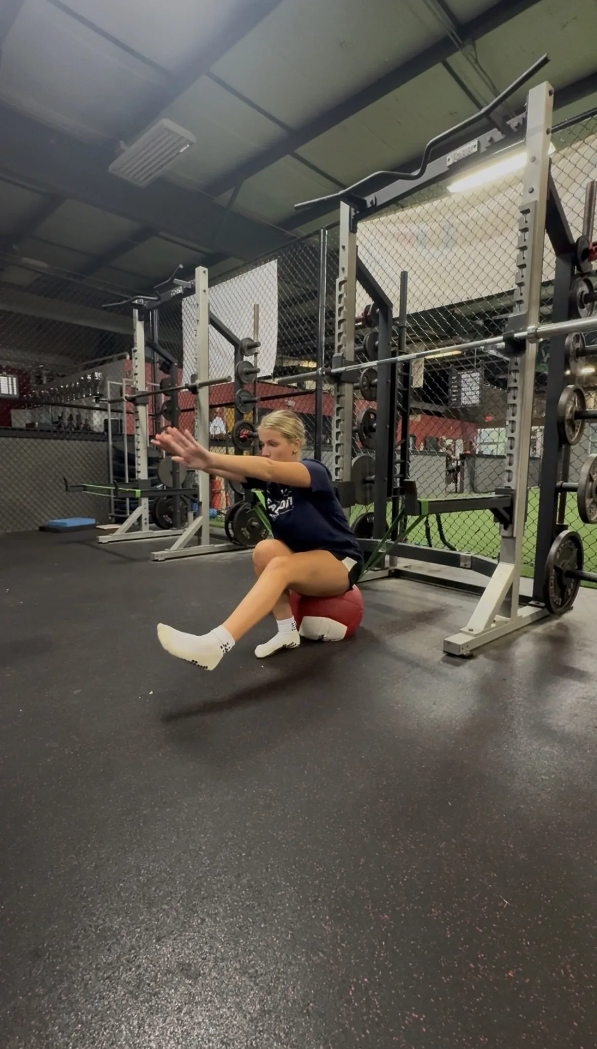 An athlete lowering under control into a single-leg squat to a medicine ball