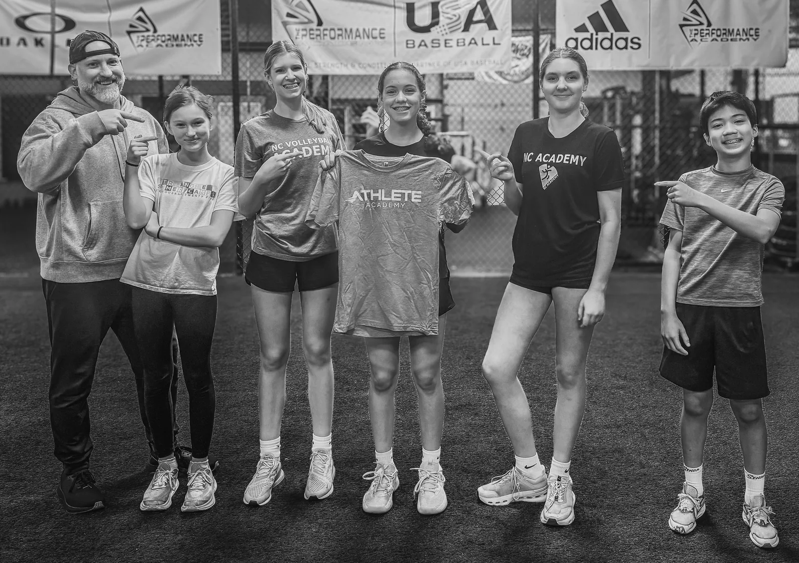 Coach Aaron Larmore standing with a group of Athlete Academy athletes on the training turf